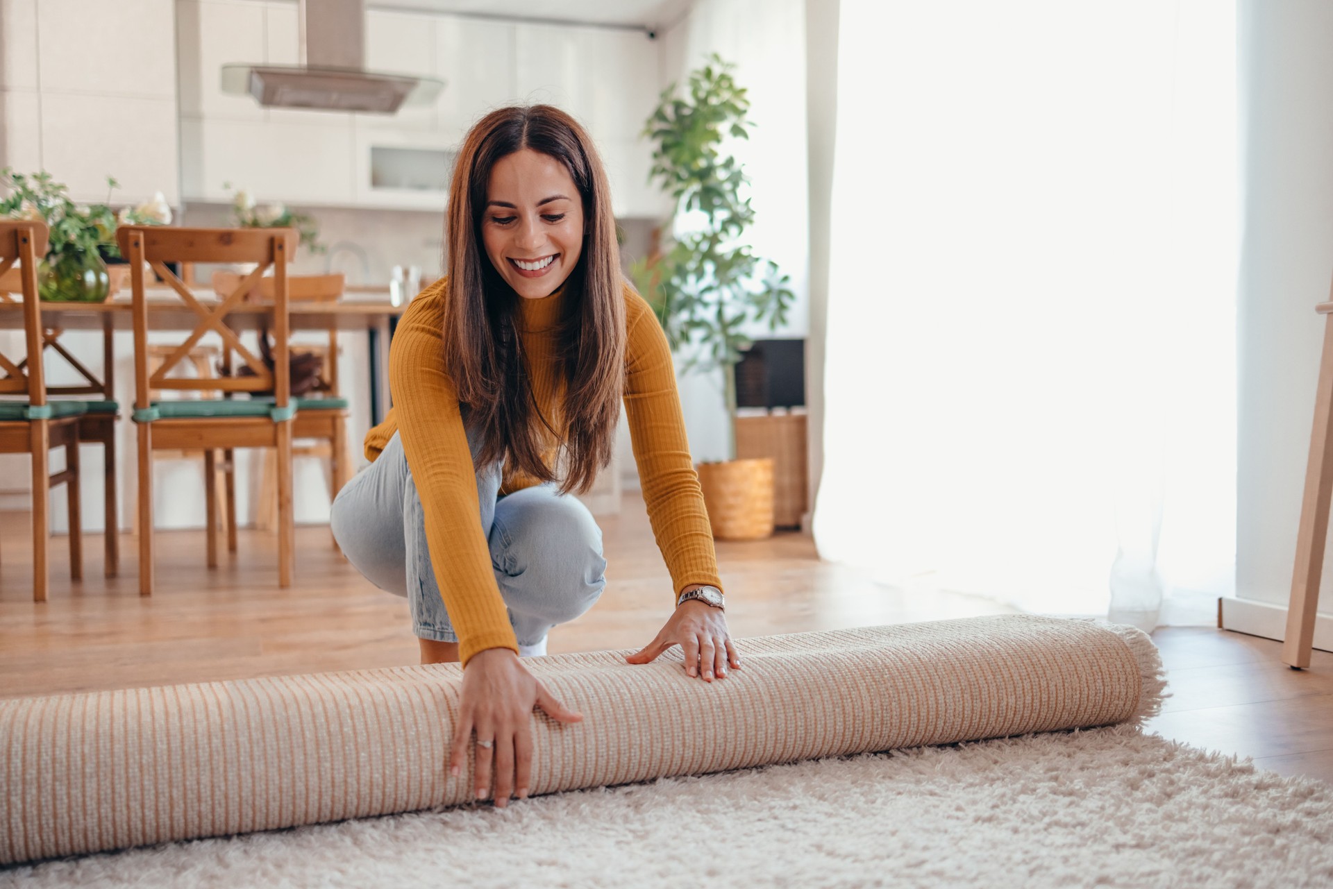 Happy Woman Unrolling Carpet in Bright Modern Living Room